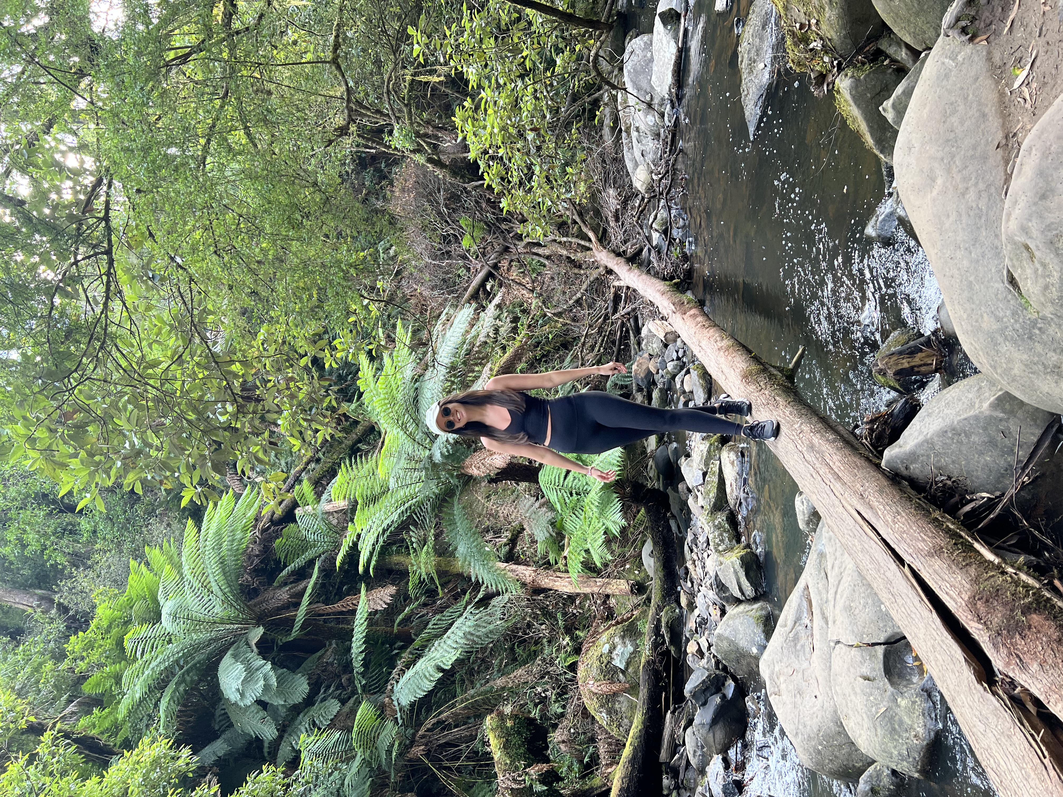 Georgia Nash, a HOKA Runaway Sydney Half Marathon fundraiser, balances herself on a fallen tree stump at a lake.